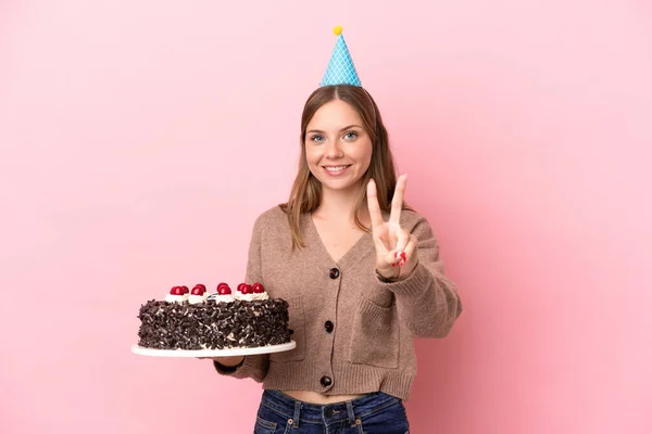 Młoda Litwinka Trzyma Tort Urodzinowy Różowym Tle Uśmiechnięta Pokazująca Znak — Zdjęcie stockowe