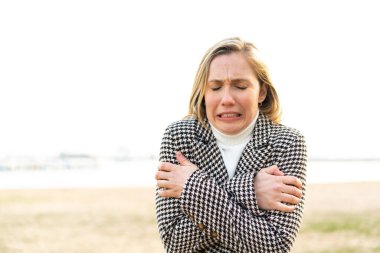 Açık havada donmakta olan genç sarışın kadın.