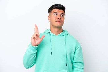 Beyaz arka planda izole edilmiş beyaz tenli yakışıklı genç adam, şans diliyor ve en iyisini diliyor.