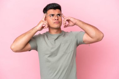 Pembe arka planda soyutlanmış beyaz, yakışıklı genç bir adam. Şüpheleri ve düşünceleri var.