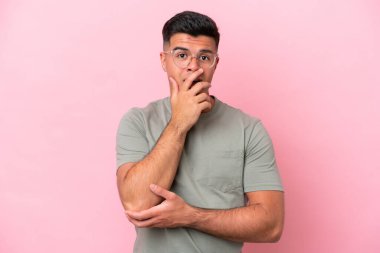 Pembe arka planda izole edilmiş beyaz, yakışıklı genç adam sağa bakarken şaşırmış ve şok olmuştu.