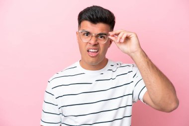Young caucasian handsome man isolated on pink background With glasses and frustrated expression