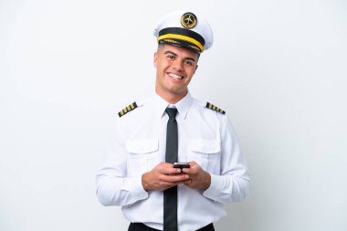 Beyaz arka planda izole edilmiş bir uçak pilotu cep telefonuyla mesaj gönderiyor.