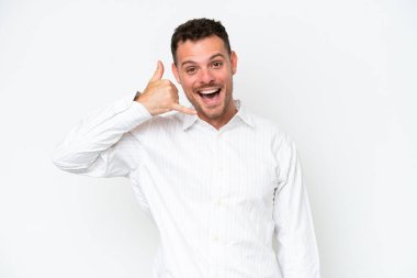 Beyaz arka planda izole edilmiş beyaz, yakışıklı genç bir adam telefon jesti yapıyor. Bana geri dönüş işareti ver.