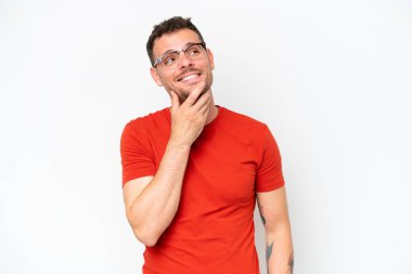 Beyaz arka planda soyutlanmış beyaz tenli yakışıklı adam gülümserken yukarı bakıyor.