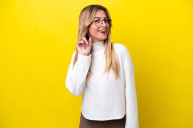 Young Uruguayan woman isolated on yellow background laughing