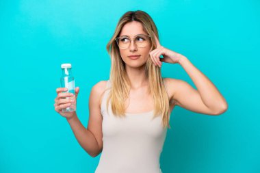 Mavi arka planda bir şişe suyu olan genç Uruguaylı kadının şüpheleri ve düşünceleri var.