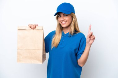 Genç Uruguaylı kadın beyaz arka planda izole edilmiş bir paket yiyecek alıyor ve en iyinin işareti olarak parmağını kaldırıyor.