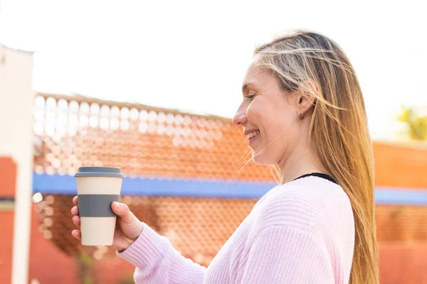 Молодая Блондинка Держит Кофе Открытом Воздухе Счастливым Выражением Лица — стоковое фото