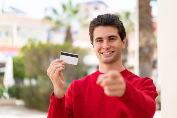 Młody Przystojny Mężczyzna Trzyma Kartę Kredytową Świeżym Powietrzu Wskazuje Palcem — Zdjęcie stockowe