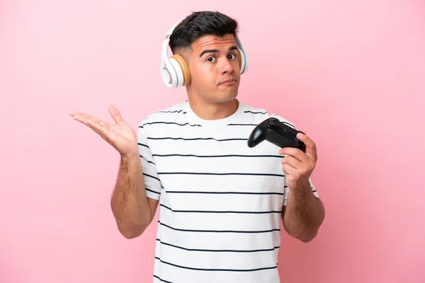 Νεαρός Όμορφος Άνδρας Παίζει Ένα Χειριστήριο Βιντεοπαιχνιδιών Απομονωμένος Ροζ Φόντο — Φωτογραφία Αρχείου