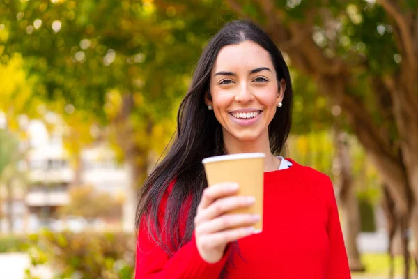 stock image Young woman holding a take away coffee at outdoors with happy expression