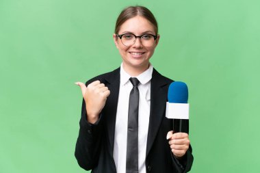 Genç TV sunucusu Kafkas kadın tecrit edilmiş arka planda bir ürün sunmak için kenarı işaret ediyor