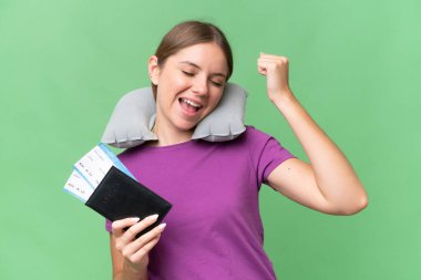 Young beautiful blonde woman with Inflatable travel Pillow over isolated background celebrating a victory