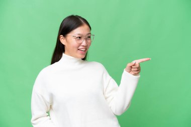 Tecrit edilmiş bir geçmişi olan genç Asyalı kadın bir ürünü sunmak için kenarı işaret ediyor.