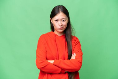 Asyalı genç bir kadın izole edilmiş arka planda mutlu bir ifadeyle öne bakıyor.