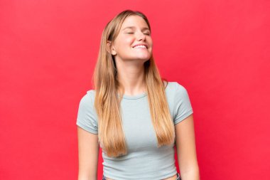 Genç ve güzel bir kadın kırmızı arka planda yalnız gülüyor.