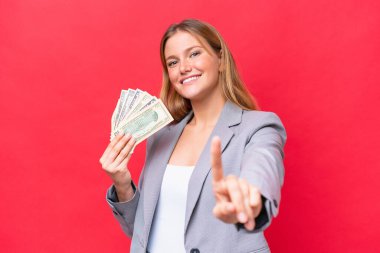 Kafkasyalı genç bir kadının elinde kırmızı arka planda izole edilmiş para var.