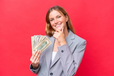 Kafkasyalı genç bir kadın elinde para tutuyor kırmızı arka planda mutlu ve gülümsüyor.
