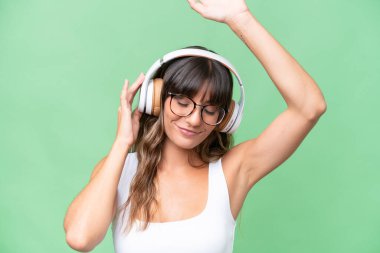 İzole edilmiş arka planda genç beyaz kadın müzik ve dans dinliyor.