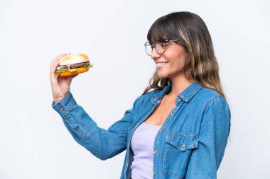 Beyaz arka planda mutlu bir ifadeyle izole edilmiş hamburger tutan beyaz bir kadın.