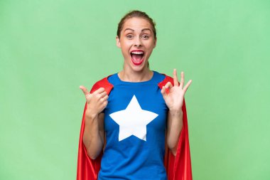 Süper kahraman beyaz kadın izole edilmiş arka planda tamam işareti ve baş parmak hareketi gösteriyor.