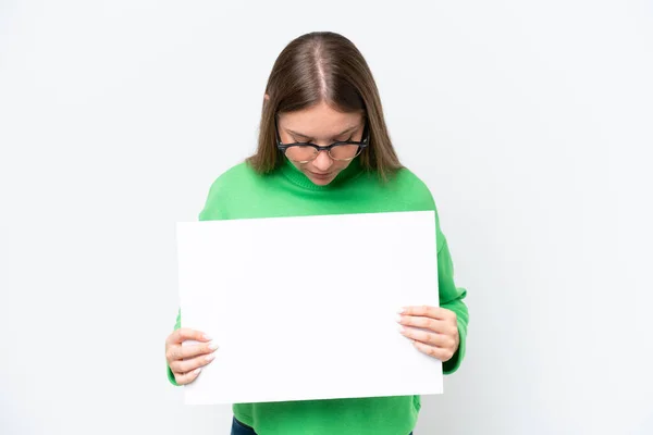 Mladá Běloška Izolovaná Bílém Pozadí Drží Prázdný Plakát Dívá Něj — Stock fotografie