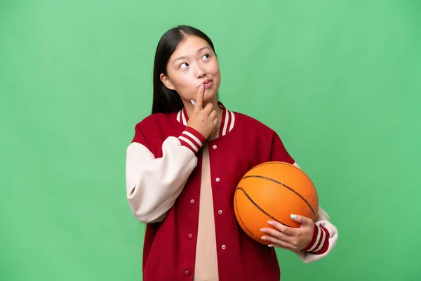 若いですバスケットボールプレーヤーアジアの女性上の隔離された背景持っています疑問ながら見上げます — ストック写真