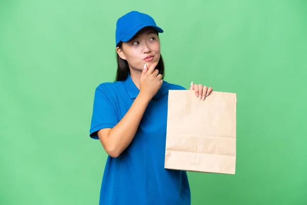 年轻的亚洲女人拿着一袋外卖食品 越过孤立的背景 抬头看 — 图库照片