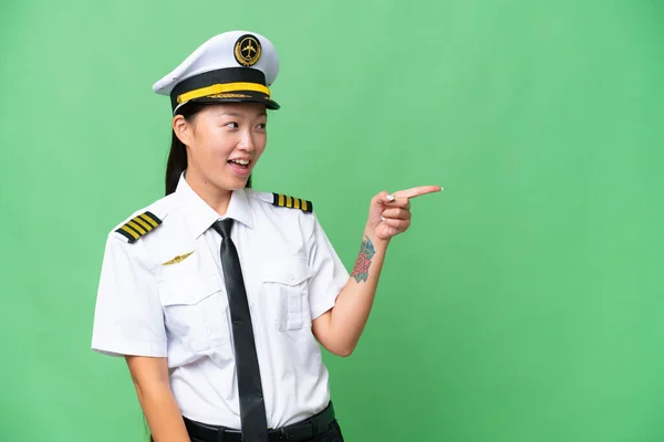 飞机驾驶员亚洲女人克服了孤立的背景 指指点点侧面 展示了一种产品 — 图库照片