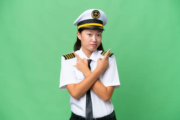 飞机驾驶员亚洲女人越过孤立的背景 指向有疑问的侧翼 — 图库照片