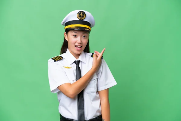 飞机驾驶员亚洲妇女克服孤立的背景惊讶而指向一侧 — 图库照片