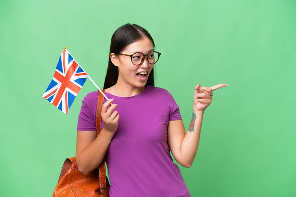 イギリスの国旗を手にした若いアジア人女性が 指を横に向けて製品を発表する — ストック写真
