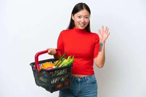 年轻的亚洲女人提着一篮子被白色背景隔离的食物 带着愉快的表情手牵着手问安 — 图库照片