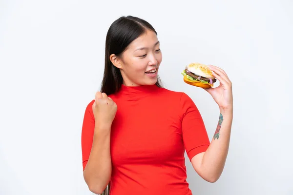 Young Asian Woman Holding Burger Isolated White Background Celebrating Victory — Foto de Stock