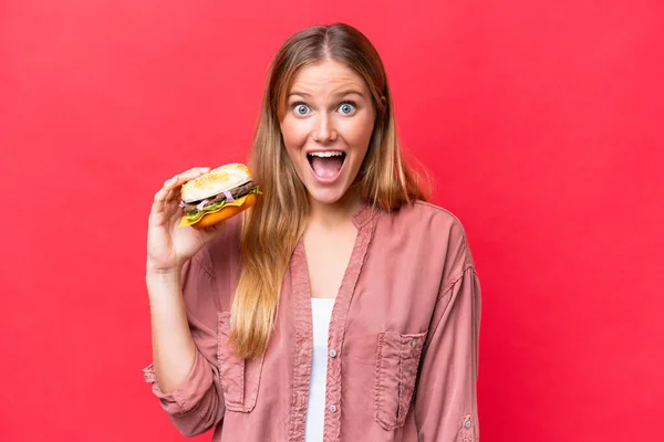 Jeune Femme Caucasienne Tenant Hamburger Isolé Sur Fond Rouge Avec — Photo