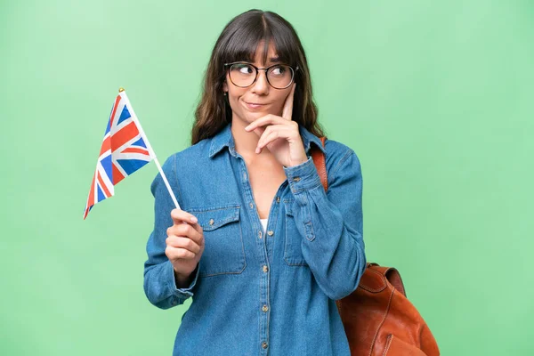Mladá Běloška Drží Britskou Vlajku Nad Izolovaným Pozadím Pochybuje Přemýšlí — Stock fotografie