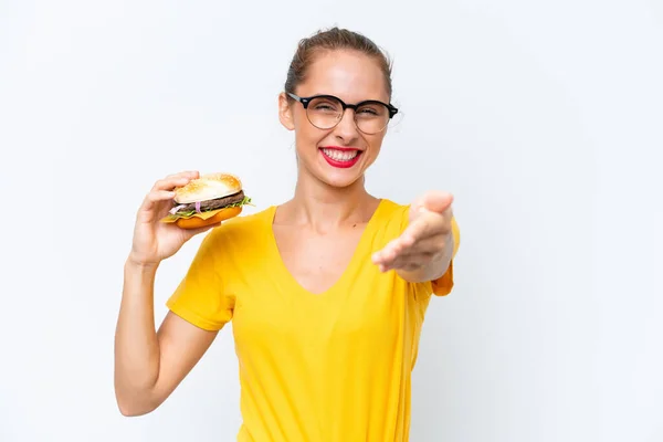 Młoda Kaukaska Kobieta Trzyma Hamburgera Odizolowanego Białym Tle Ściskając Dłonie — Zdjęcie stockowe