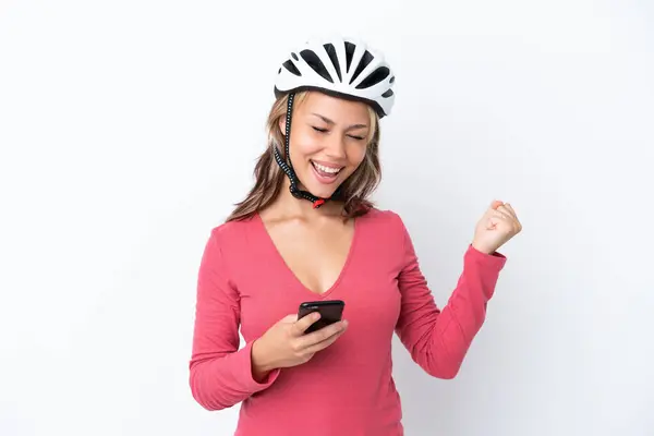若いですロシアの女性を身に着けています自転車ヘルメットは勝利の位置で携帯電話と白の背景に隔離 — ストック写真