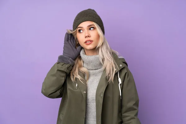 Teenager Blonde Mädchen Mit Wintermütze Über Isolierten Lila Hintergrund Hören — Stockfoto