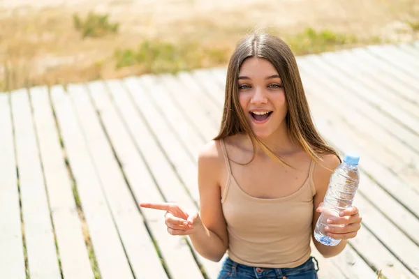 Tiener Meisje Met Een Fles Water Buiten Verrast Wijzend Vinger — Stockfoto