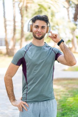 Açık havada kulaklıkla müzik dinleyen bir adam.