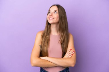 Genç Litvanyalı kadın mor arka planda izole edilmiş gülümserken yukarı bakıyor