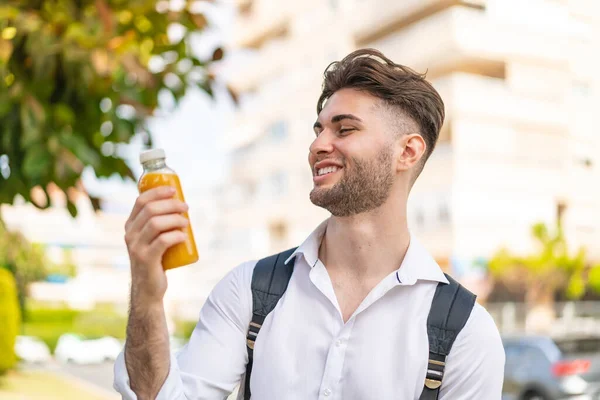 年轻英俊的男子在户外拿着橙汁 满面春风 — 图库照片