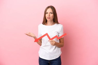 Genç Litvanyalı bir kadın pembe arka planda izole edilmiş, aşağıya doğru ok atıyor ve üzgün bir ifadeyle