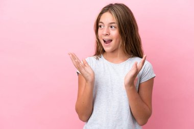 Küçük beyaz kız pembe arka planda izole edilmiş ve yüzünde sürpriz bir ifade var.