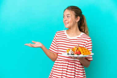 Mavi arka planda gözleme tutan beyaz bir kız. Sürpriz bir ifadeyle yan tarafa bakarken.