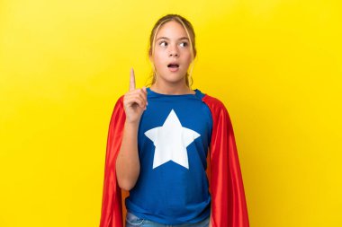 Süper kahraman küçük kız sarı arka planda izole edilmiş.