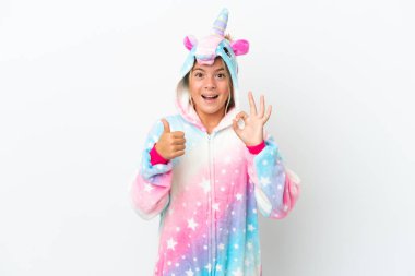 Beyaz arka planda izole edilmiş tek boynuzlu at pijamalı küçük kız işaret ve baş parmak hareketi gösteriyor.