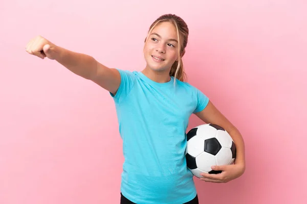 小さなサッカー選手の女の子孤立しました上のピンクの背景与えますA親指アップジェスチャー — ストック写真